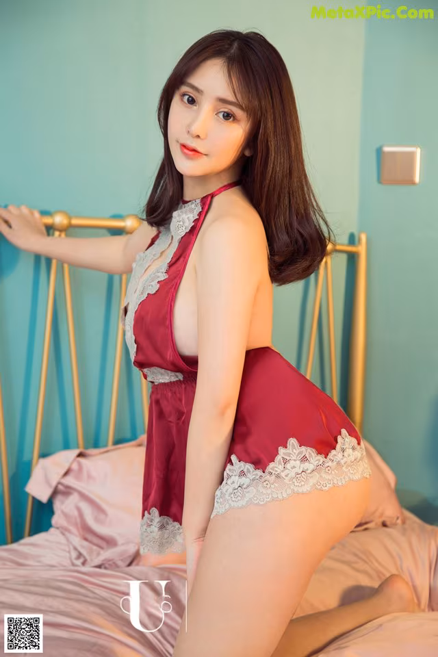 A woman in a red lingerie posing on a bed.