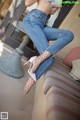 A woman sitting on a couch wearing fishnet stockings and high heels.