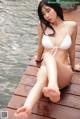 A woman in a white bikini sitting on a dock.