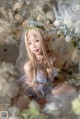 A woman in a wedding dress sitting on a bed of flowers.