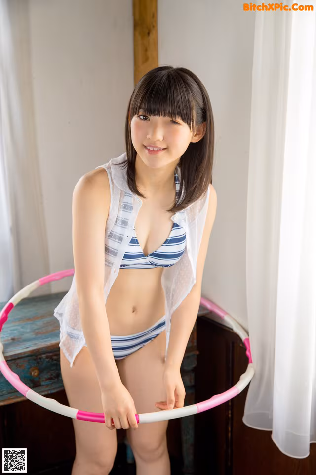 A woman in a bikini holding a hula hoop.