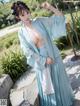 A woman in a blue hanfu is posing for the camera.