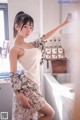 A woman in a white tank top and floral skirt posing in a kitchen.