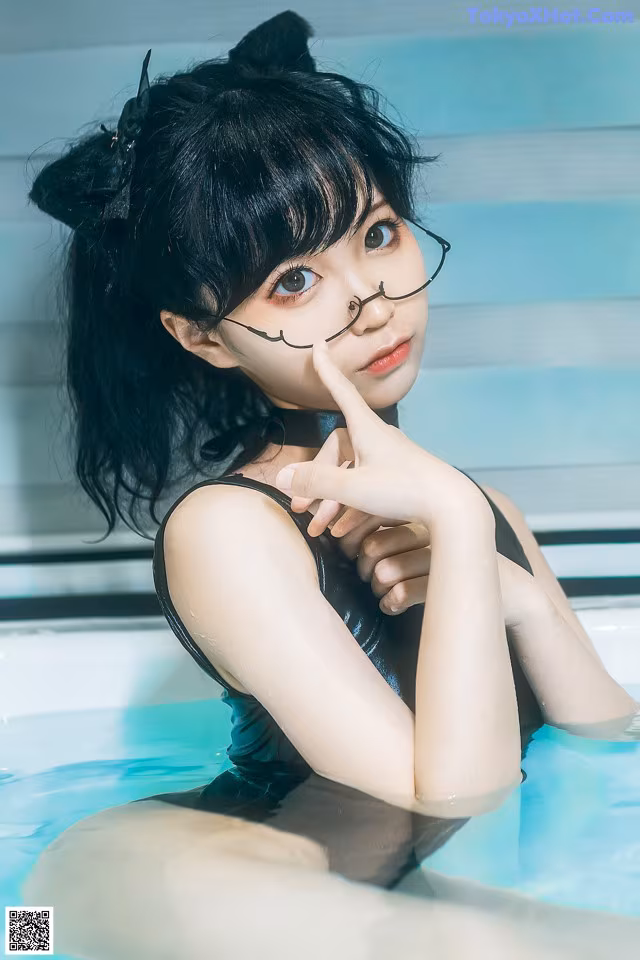 A woman in a black bathing suit sitting in a pool.