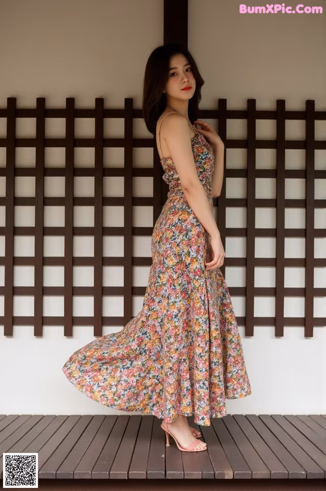 A woman standing on a wooden platform in a floral dress.