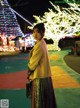 A woman standing in front of a christmas tree at night.