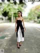 A woman in a black and white dress is walking down the street.