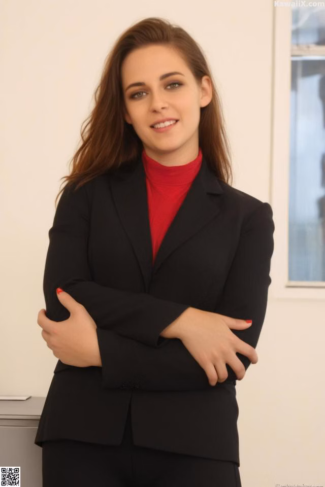 A woman in a black suit standing with her arms crossed.