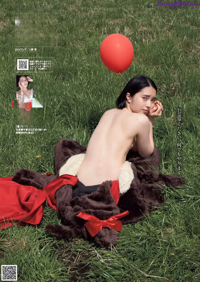 A naked woman laying in the grass with a red balloon.