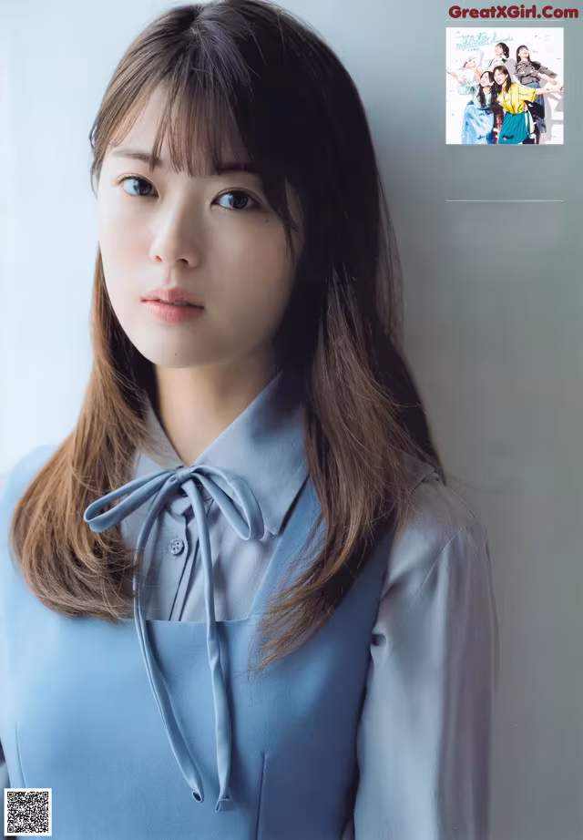 A woman in a blue shirt is posing for a magazine.