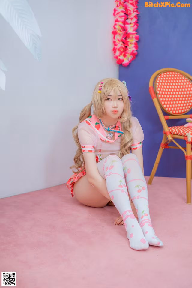 A woman sitting on a pink floor next to a chair.