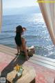 A woman sitting on a wooden deck next to the ocean.