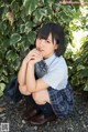 A woman in a school uniform sitting on the ground.