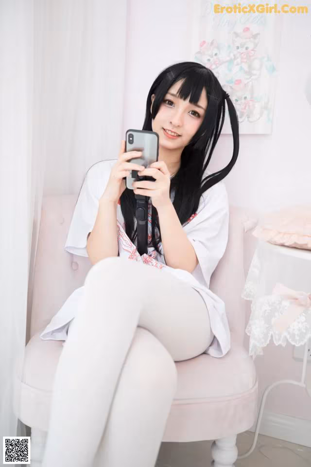 A woman sitting on a pink chair holding a cell phone.