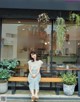 A woman sitting on a bench in front of a spread restaurant.