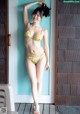 A woman in a yellow bikini standing in front of a door.