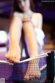 A woman sitting on top of a table tennis net.