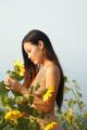 A naked woman standing in a field of sunflowers.