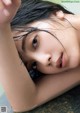 A young woman laying in a bathtub with wet hair.