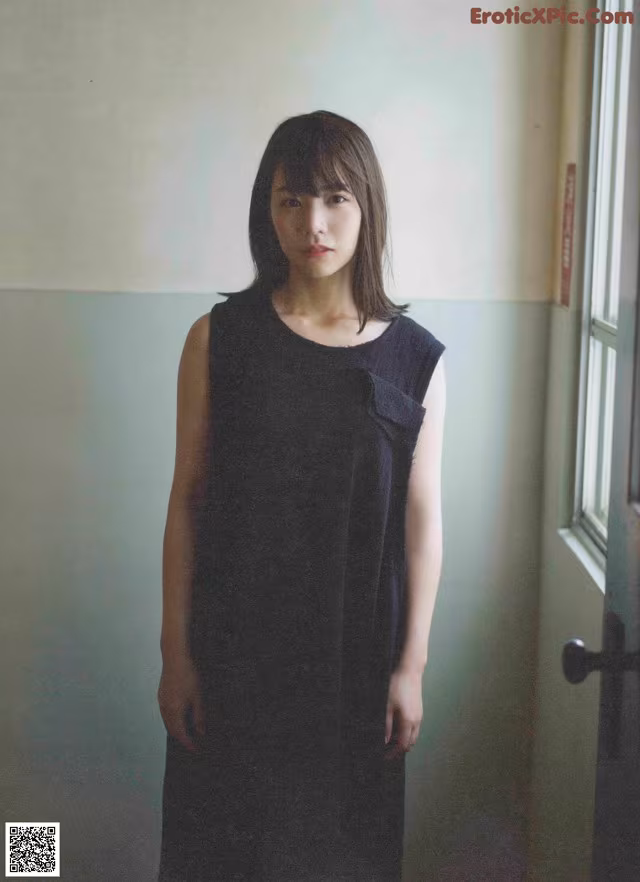 A woman in a black dress standing in front of a door.