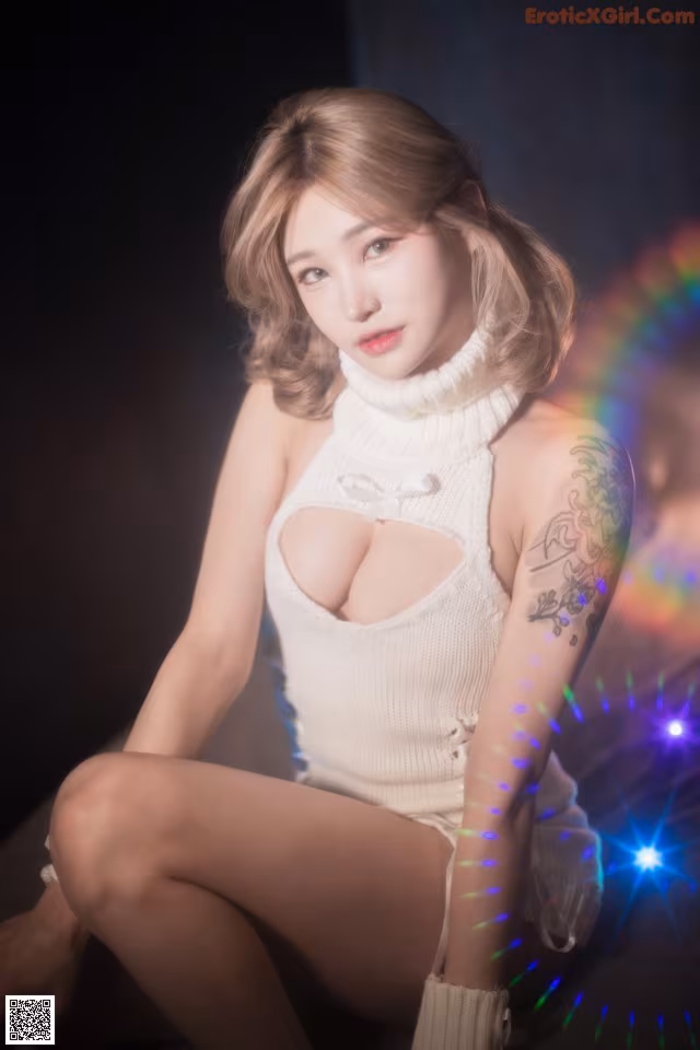 A woman in a white dress sitting on a chair.