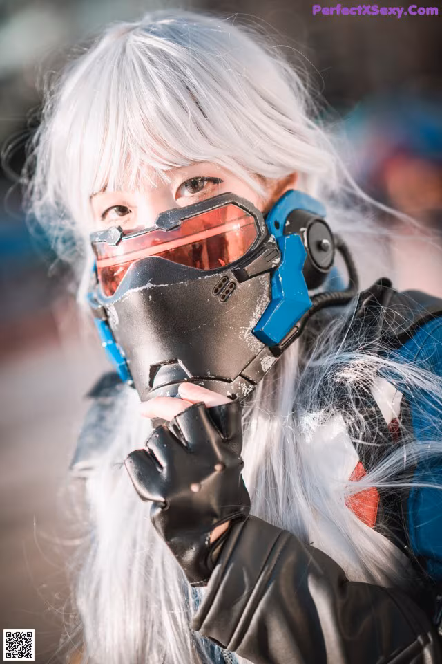 A woman with white hair wearing a mask and gloves.