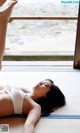 A woman laying on a tatami mat in front of a window.